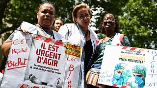 Protestors hold signs reading "It's urgent to act" in support of French hospital staff in Paris