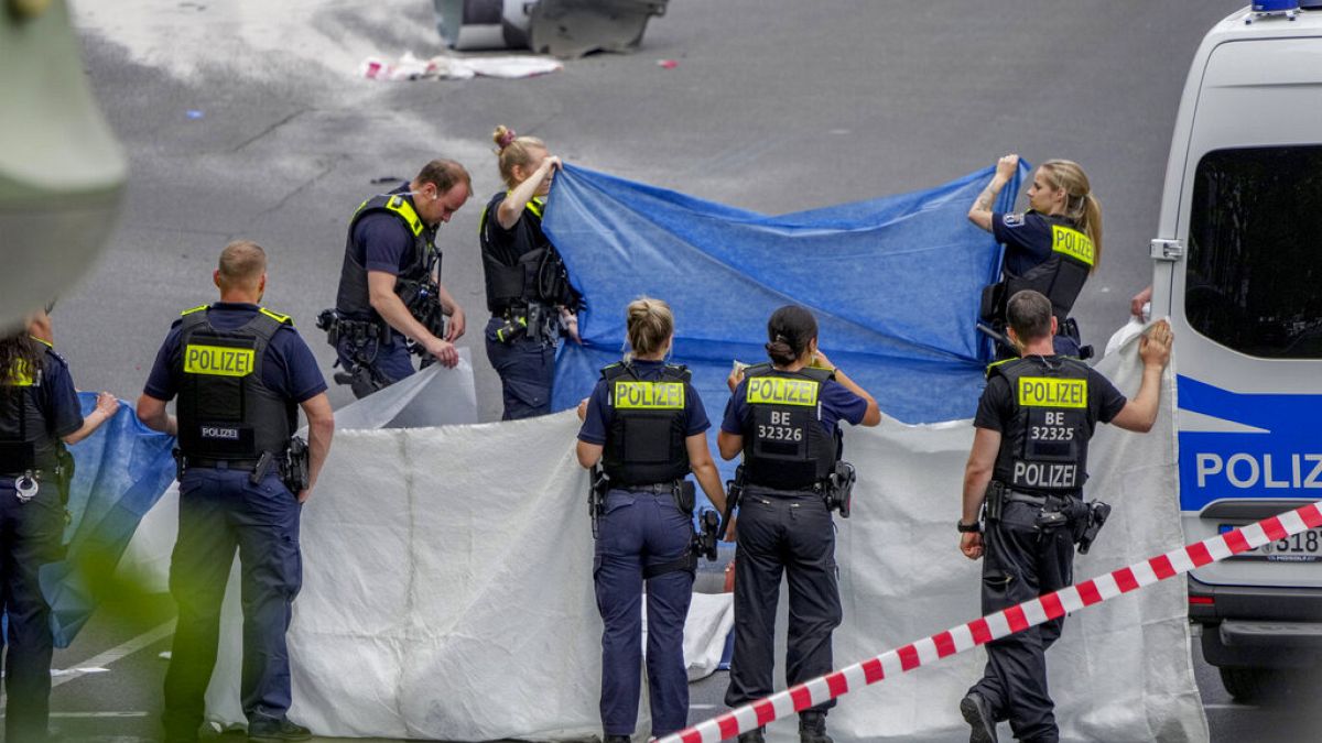 Agentes de policía cubren un cadáver después de que un coche se estrellara contra una multitud en el centro de Berlín, Alemania, el miércoles 8 de junio de 2022.