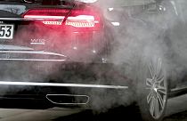 A luxury car is surrounded by exhaust gases as it is parked with a running engine in Berlin, Germany