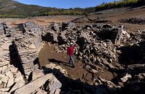 A man walks among the ruins of the previously-submerged village of Vilar. It has risen above the waters of the Zezere River due to drought. Feb. 17, 2022.