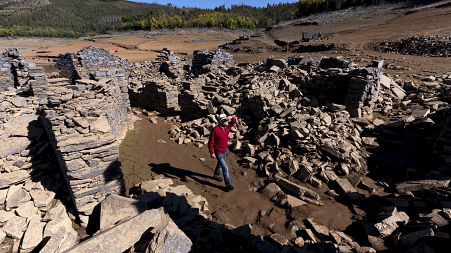 A man walks among the ruins of the previously-submerged village of Vilar. It has risen above the waters of the Zezere River due to drought. Feb. 17, 2022.