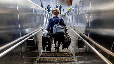 A woman carries her luggage down the stairs at the international airport in Frankfurt, Germany.