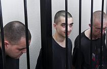 Los ciudadanos británicos Aiden Aslin, a la izquierda, y Shaun Pinner, a la derecha, y el marroquí Saaudun Brahim, en el centro, sentados en un tribunal de Donetsk