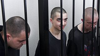 Los ciudadanos británicos Aiden Aslin, a la izquierda, y Shaun Pinner, a la derecha, y el marroquí Saaudun Brahim, en el centro, sentados en un tribunal de Donetsk