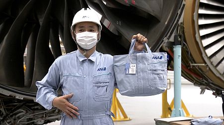 An ANA worker models a bag made from his recycled workwear