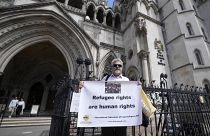 Protestors stand outside The Royal Court of Justice in London, Friday, June 10, 2022. Several NGOs lost a challenge opposing the Home Office's new asylum deal with Rwanda.