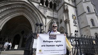 Protestors stand outside The Royal Court of Justice in London, Friday, June 10, 2022. Several NGOs lost a challenge opposing the Home Office's new asylum deal with Rwanda.