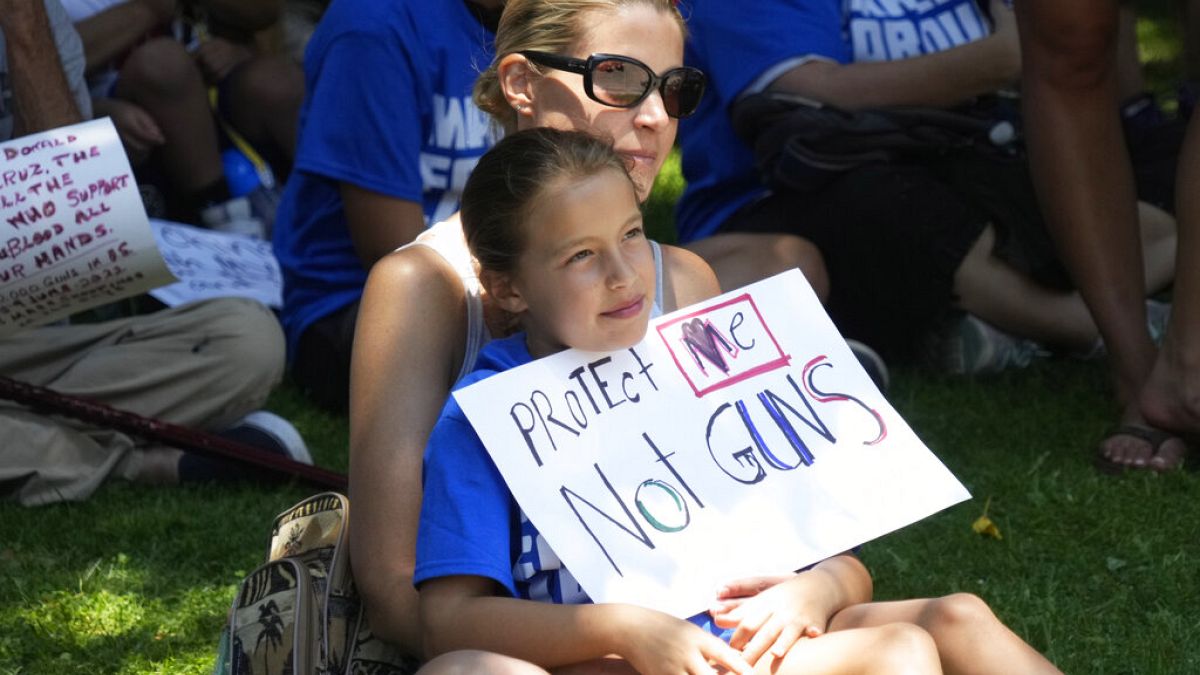 Una niña con un cartel que lee "Protéjanme a mi, no a las armas"