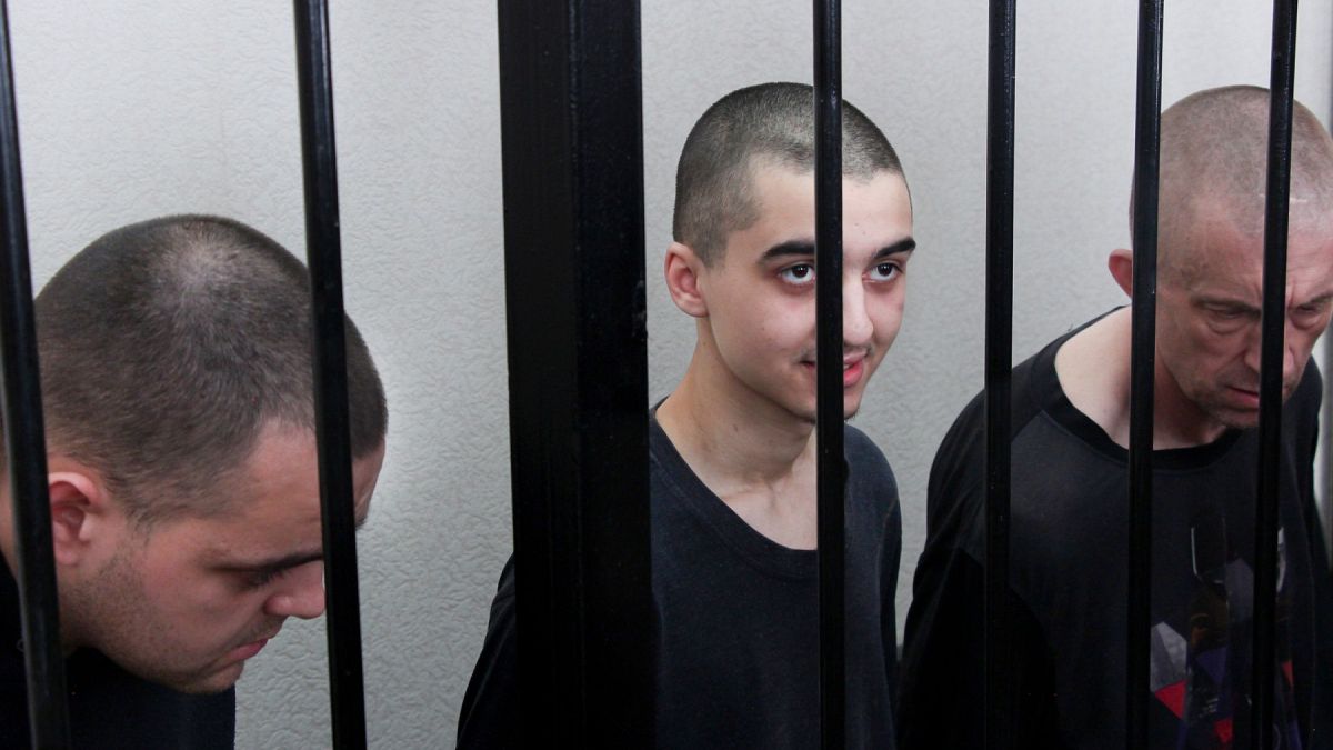 Britons Aiden Aslin, Shaun Pinner and Moroccan Brahim Saadoun sit behind bars during trial in the DNR, 9 June 2022