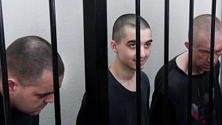 Britons Aiden Aslin, Shaun Pinner and Moroccan Brahim Saadoun sit behind bars during trial in the DNR, 9 June 2022