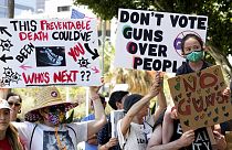 Protesters hold up signs during a gun control rally outside City Hall in Los Angeles