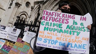 A protester stands outside the High Court where the ruling on Rwanda deportation flights is taking place, in London Monday, June 13, 2022