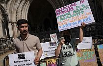 Des manifestants se tiennent devant la Haute Cour où se déroule le jugement sur les vols d'expulsion du Rwanda, à Londres, lundi 13 juin 2022.