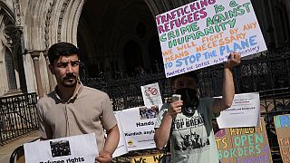 Des manifestants se tiennent devant la Haute Cour où se déroule le jugement sur les vols d'expulsion du Rwanda, à Londres, lundi 13 juin 2022.
