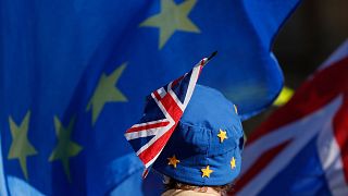 یک تظاهر کننده طرفدار اتحادیه اروپا پرچم اتحادیه اروپا به شکل کلاه و پرچم بریتانیا که به آن چسبانده شده است.