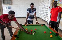 Peter Nyuoni, right, from Sudan, who was evacuated from Libya to Rwanda, plays pool with others at the Gashora transit centre for refugees and asylum-seekers, June 10, 2022.