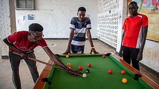 Peter Nyuoni, right, from Sudan, who was evacuated from Libya to Rwanda, plays pool with others at the Gashora transit centre for refugees and asylum-seekers, June 10, 2022.