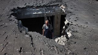 A man examines the roof of a hospital damaged during shelling in Donetsk, eastern Ukraine, Tuesday, June 14, 2022.