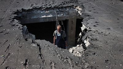 A man examines the roof of a hospital damaged during shelling in Donetsk, eastern Ukraine, Tuesday, June 14, 2022.