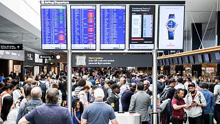 assengers wait in front of a display board at Zurich airport, in Zurich, Wednesday, June 15, 2022