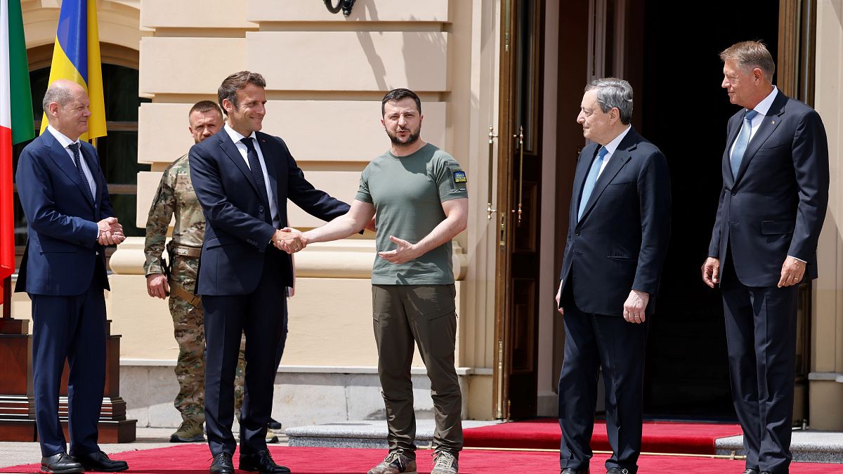 Emmanuel Macron aperta a mão a Volodymyr Zelenskyy perante o olhar de Olaf Scholz, Mario Draghi e Klaus Iohannis