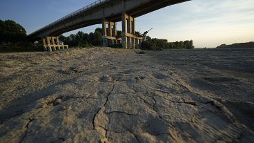 Dry cracked land sits under a bridge in Boretto on the bed of the Po river in Italy, Wednesday, June 15, 2022.