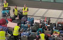 Airport staff struggle to deal with a sea of waiting luggage at Heathrow Airport