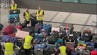 Airport staff struggle to deal with a sea of waiting luggage at Heathrow Airport 