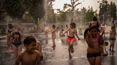 أطفال يمرحون حول نافورة في حديقة على ضفاف نهر في مدريد - إسبانيا. 2022/06/15