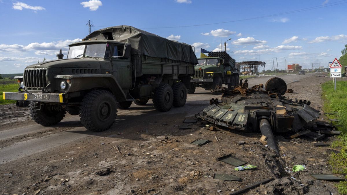 Veicoli ucraini passato davanti a un carro armato russo distrutto