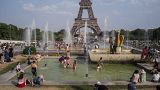 People enjoy the sun and the fountains of the Trocadero gardens in Paris.