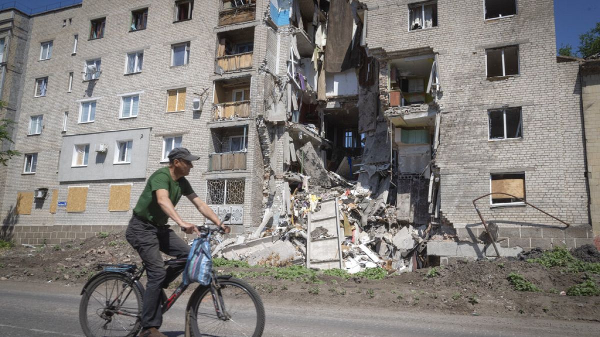 Radfahrer und zerstörtes Haus in Donezk in der Ukraine