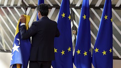 A member of protocol sets out EU and Bosnian flags prior to arrivals for an EU summit in Brussels, 23 June 2022