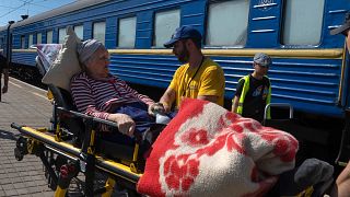 Волонтеры помогают пожилой женщине, эвакуированной из зоны боевых действий, сесть на поезд в Покровске, восточная Украина.