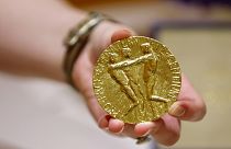 A worker holds Dmitry Muratov's 23-karat gold medal of the 2021 Nobel Peace Prize before being auctioned at the Times Center, June 20, 2022, in New York