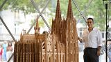 Fadel Alkhudr from Syria poses beside his wooden model of the word heritage Cologne Cathedral
