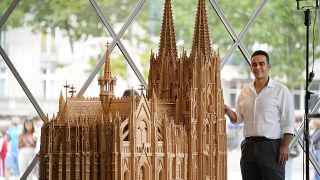 Fadel Alkhudr from Syria poses beside his wooden model of the word heritage Cologne Cathedral