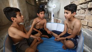 أطفال يحاولون تلطيف درجات حرارة أجسادهم في العراق