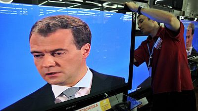 A Moscow shop assistant works on May 18, 2011, amidst TV screens during the broadcast of Russian President Dmitry Medvedev's televised news conference.