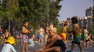 Niños y adultos se refrescan en una fuente en un parque junto al río en Madrid, España, el viernes 17 de junio de 2022.