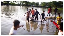 أشخاص يسيرون في مياه الفيضانات في سونامغانغ، بنغلاديش، 21 يونيو 2022