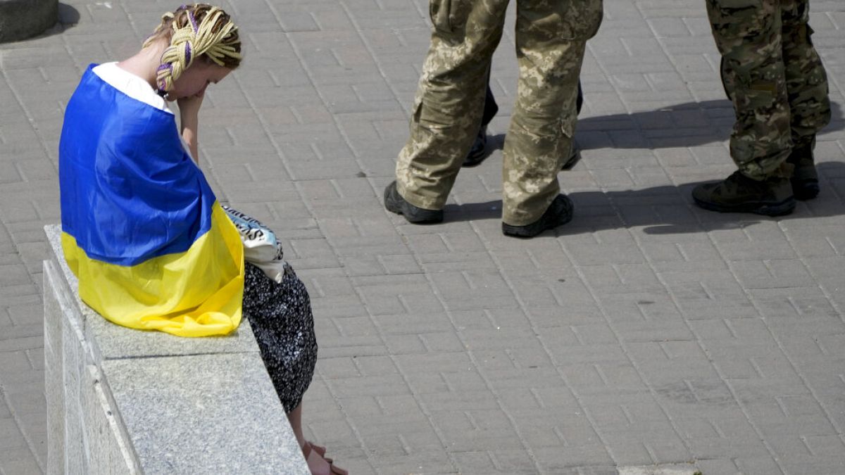Mulher com bandeira ucraniana, na Praça da Independência, em Kiev, Ucrânia