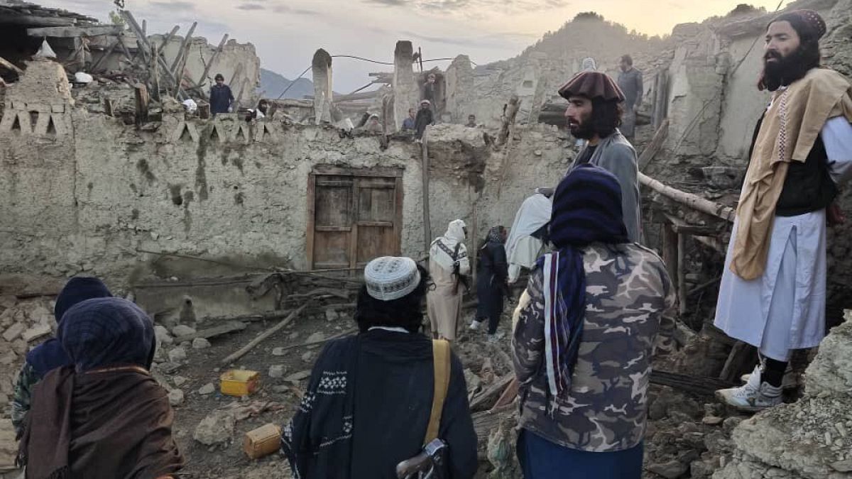 Afgánok egy, a földrengés által lerombolt ház előtt