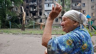 A woman gestures near an apartment building damaged during shelling in Donetsk, in territory controlled by the Donetsk People's Republic, eastern Ukraine, June 22, 2022.