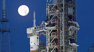 The Strawberry Supermoon sets in front of the NASA Artemis rocket with the Orion spacecraft aboard on pad 39B at the Kennedy Space Center
