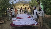 Grupo de homens permanece junto a corpos de vítimas do terramoto no Afeganistão
