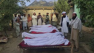 Grupo de homens permanece junto a corpos de vítimas do terramoto no Afeganistão