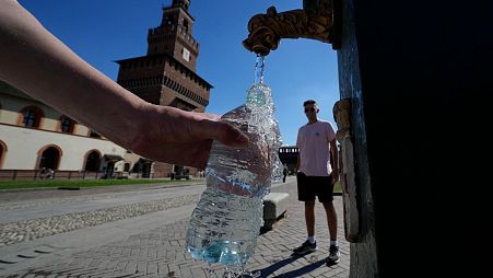Tourists fill plastic bottles with water from a public fountain at the Sforzesco Castle, in Milan, Italy.