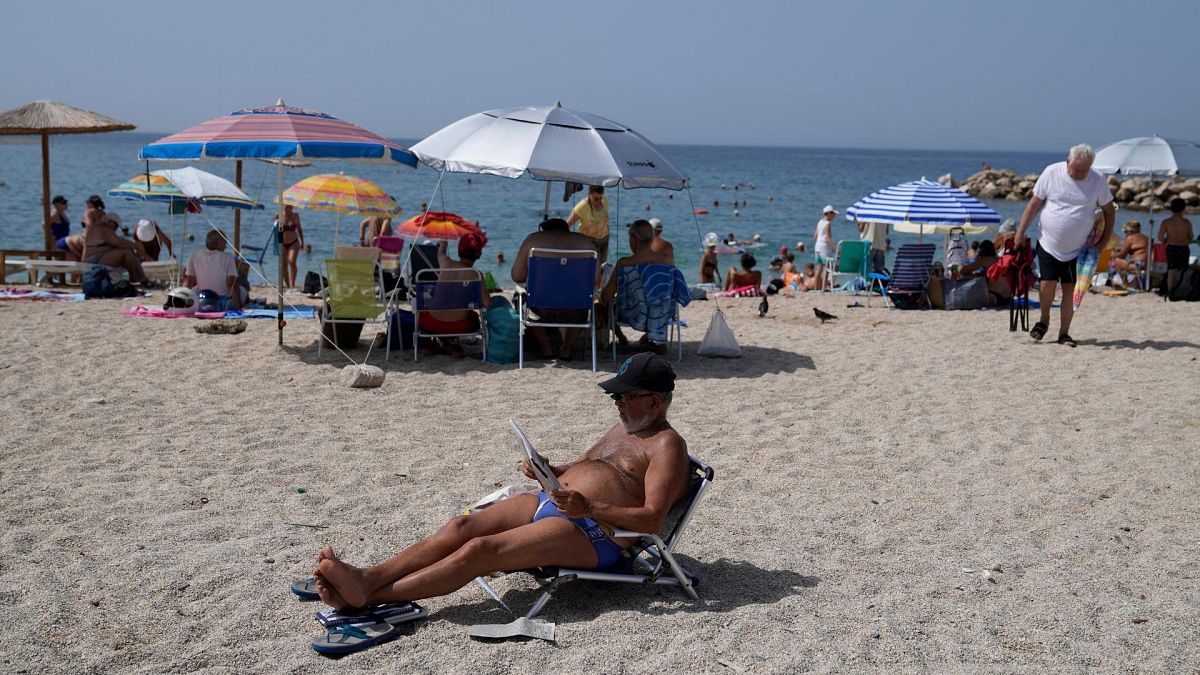 A man reads a newspaper at the public beach of Alimos, in southern Athens, Greece, on Thursday.