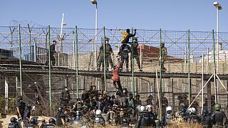 Des hommes escaladent les clôtures séparant l'enclave espagnole de Melilla du Maroc à Melilla, en Espagne, vendredi 24 juin 2022.